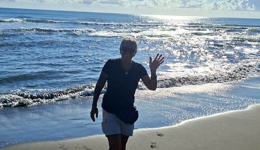 A hiker waving from the Caribbean surf