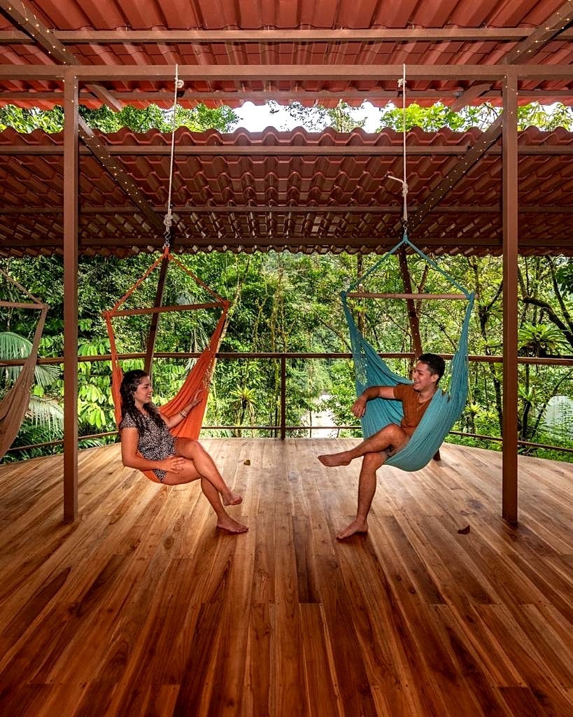 Two guests relaxing in hammocks on the wooden deck of the rancho