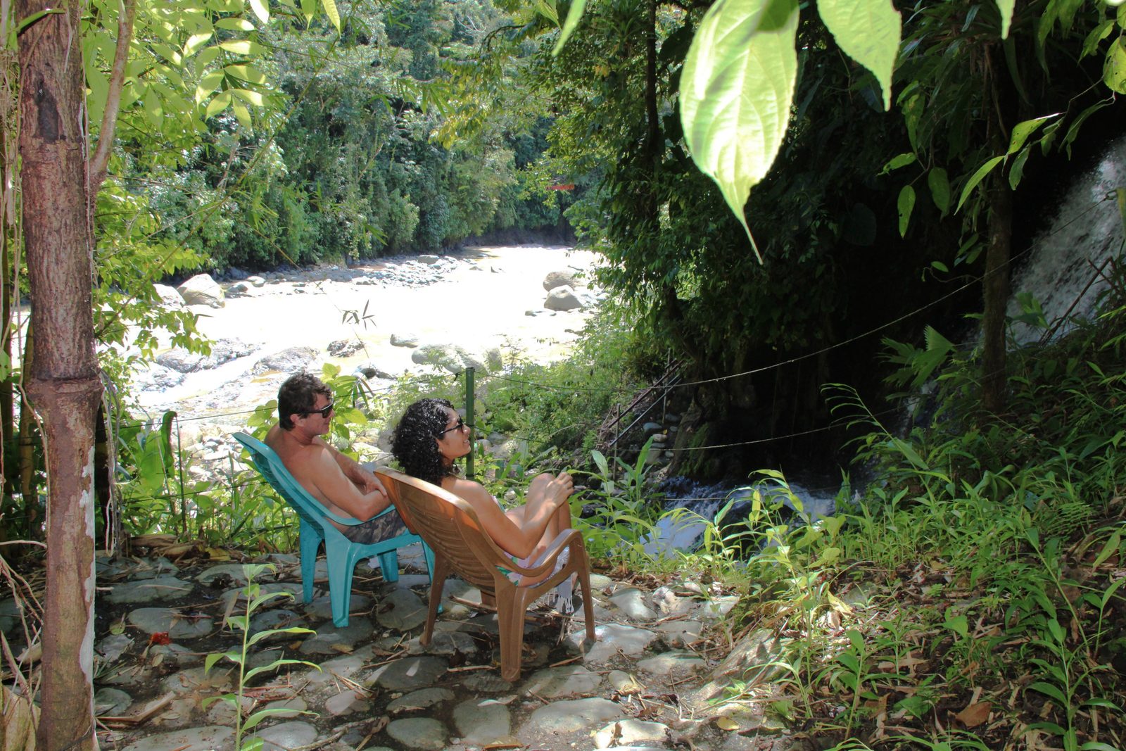 A man and a woman lounging on the patio between the rapids and the falls
