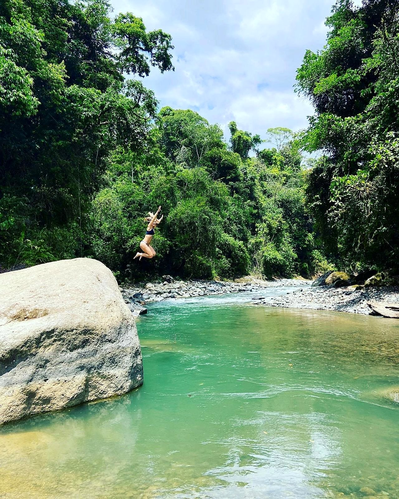 A guest jumping from a boulder into the river