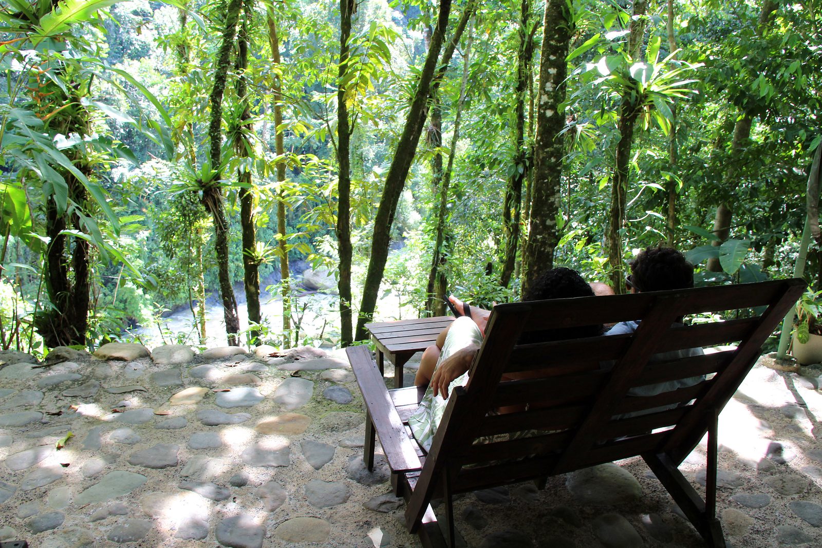 A wooden lounger on the stone terrace facing the forest