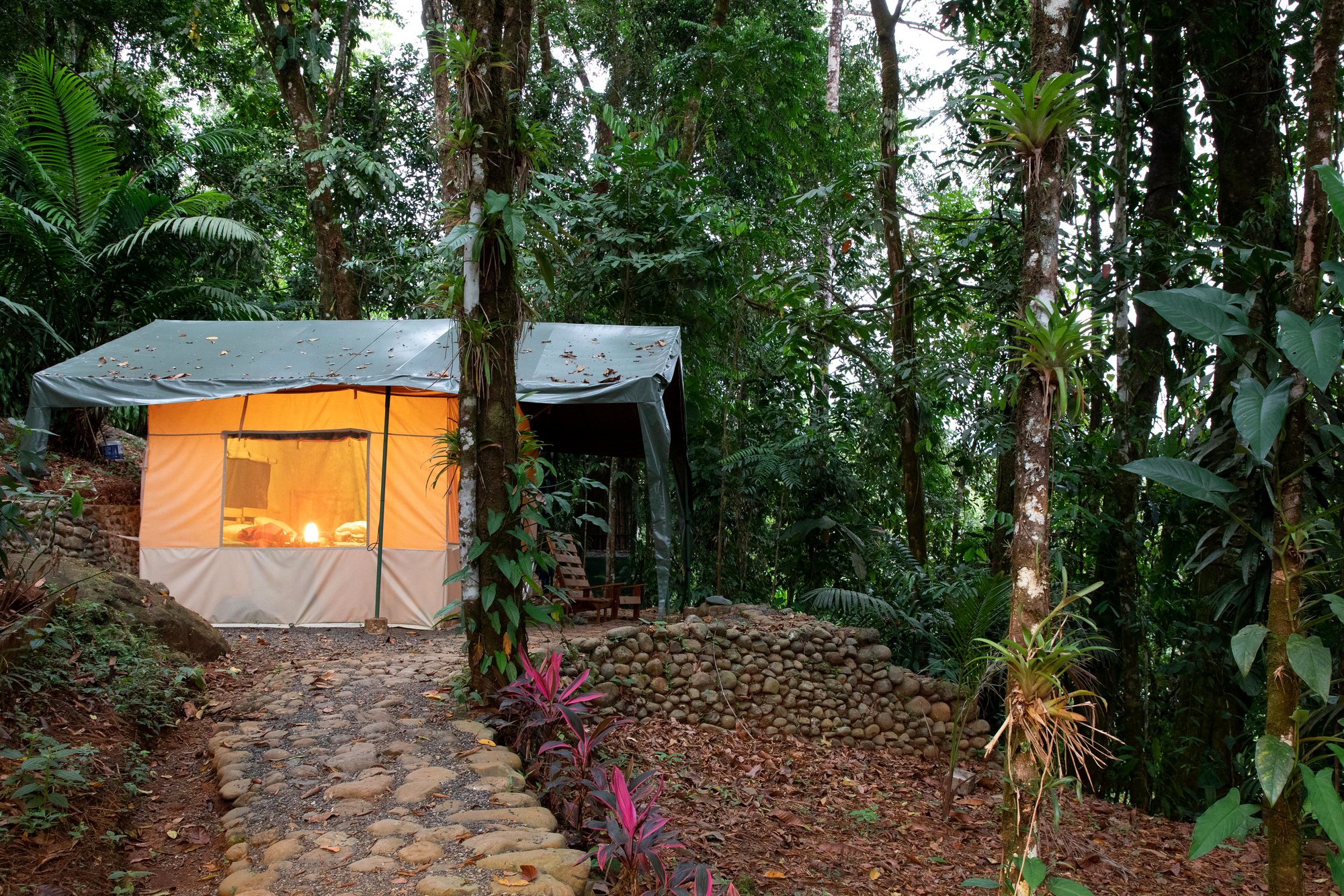Tent with its lights on at the end of a stone path