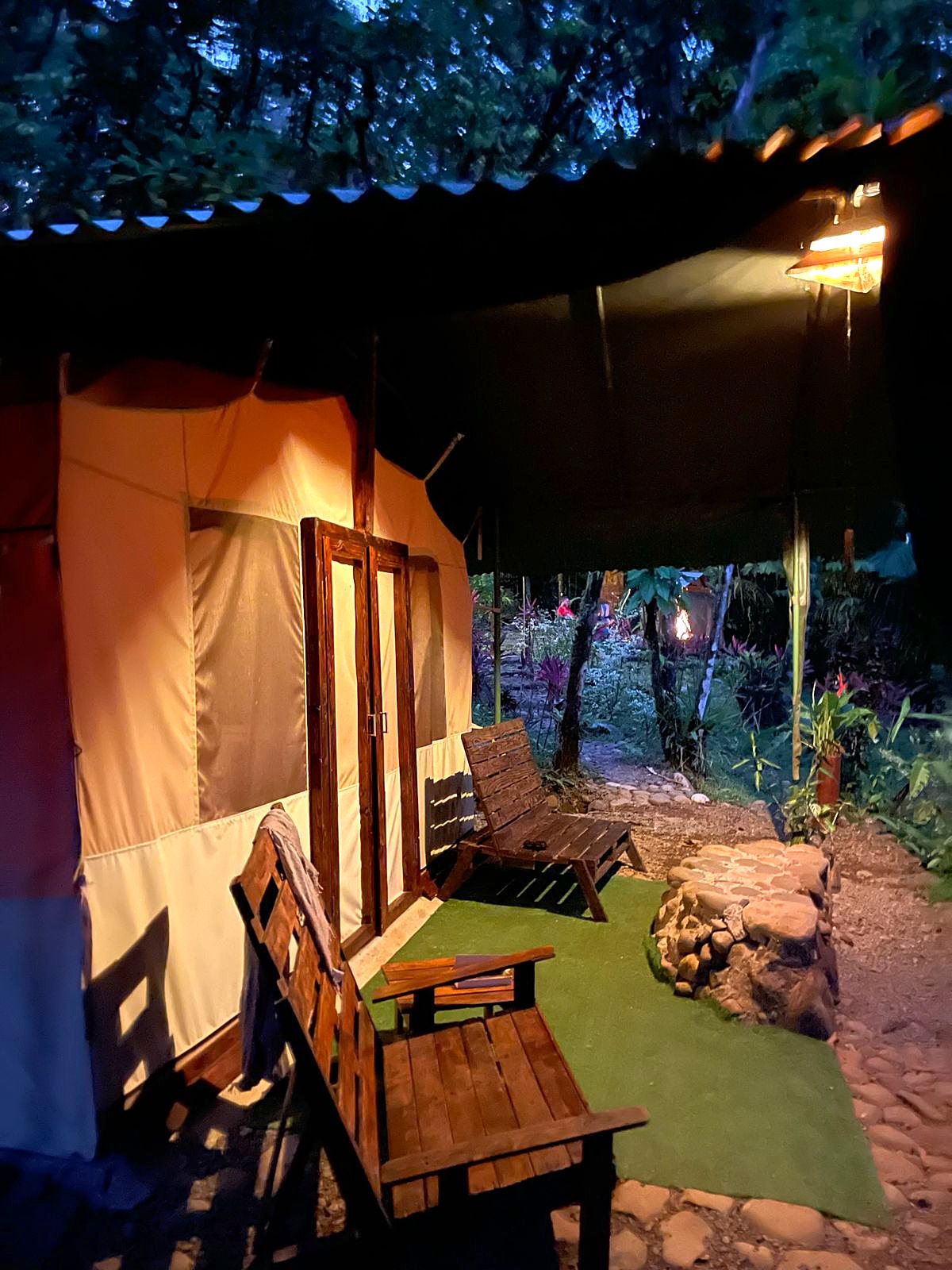 Tent porch with a wooden bench, lit at night
